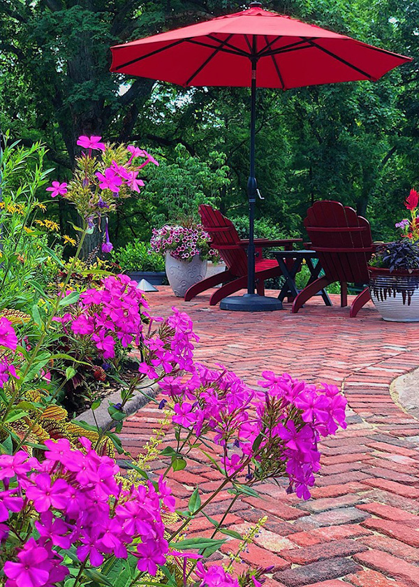 Flowers are full bloom on this gorgeous patio made of reclaimed materials