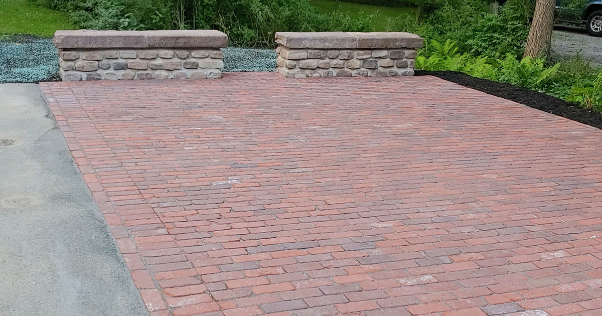 Old stone paired with historic street brick pavers create a patio full of character