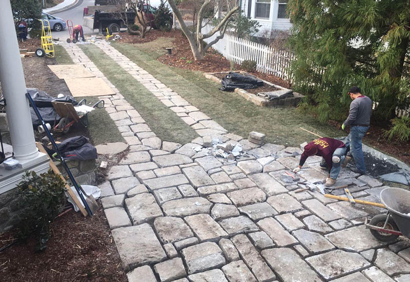 Installers add the finishing touches on this salvaged granite curb paver driveway project