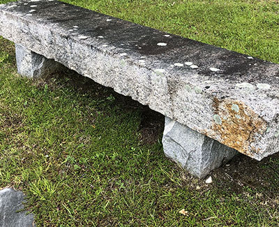 An antique piece of reclaimed granite stone used as a long, straight bench