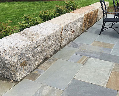 Salvaged granite large stone blocks used as a bench for charming patio