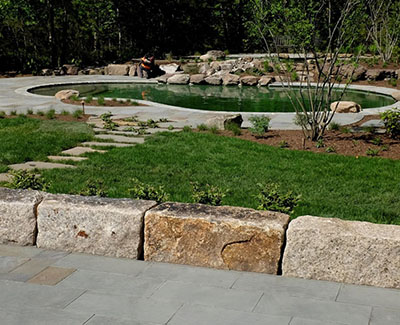 An incredible backyard landscape and hardscape featuring antique granite stone as benches