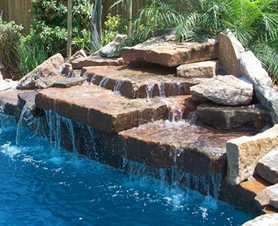 A gorgeous pool waterfall using reclaimed granite and salvaged natural limestone